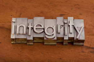 integrity word in vintage, metal letterpress printing blocks on scratched wooden background